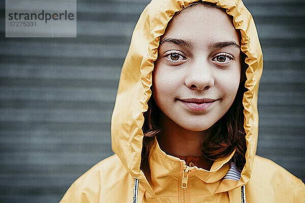 Lächelndes Mädchen im Regenmantel im Freien stehend