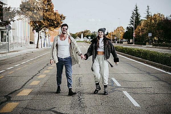 Schöne lächelnde Frau hält Hände mit männlichen Partner,  während auf der Straße in der Stadt stehen