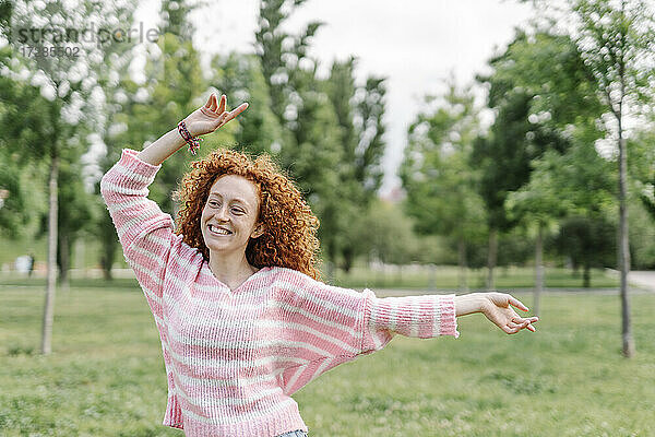 Fröhliche rothaarige Frau tanzt im Park