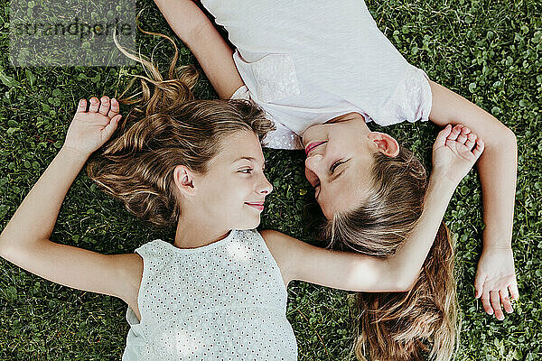 Lächelnde Mädchen,  die sich im Sommer im Gras entspannen