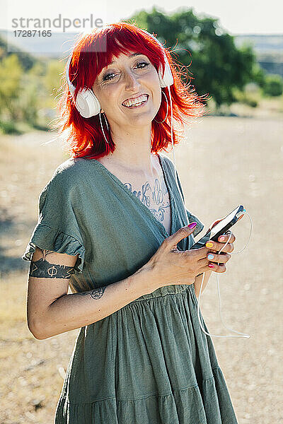 Glückliche Frau mit Smartphone an einem sonnigen Tag