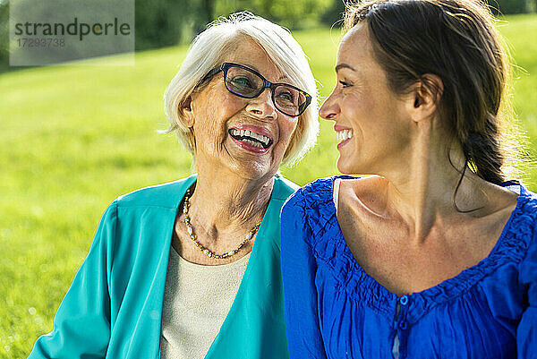 Lächelnde ältere Frau mit halbwüchsiger Frau im öffentlichen Park