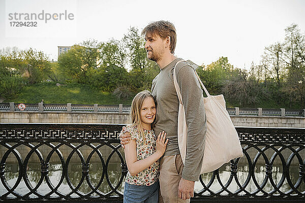 Lächelnder Vater und lächelnde Tochter stehen am Geländer