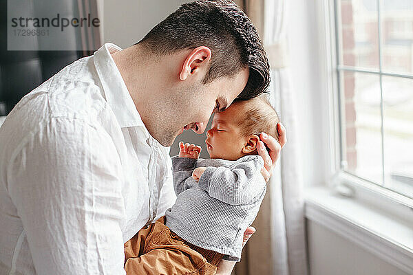 Glücklich stolzer Vater umarmt küssen neugeborenes Baby Junge. Bindung mit Kind.