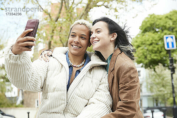 Glückliche Frau nimmt Selfie mit Freundin durch Mobiltelefon
