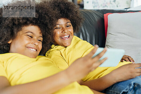 Glückliche Zwillingsbrüder benutzen ihr Smartphone zu Hause