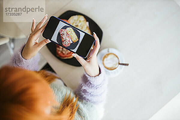 Eine Kundin fotografiert in einer Cafeteria ihr Essen mit dem Mobiltelefon