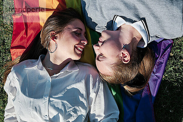 Lesbisches Paar,  das sich auf der Regenbogenfahne liegend ansieht