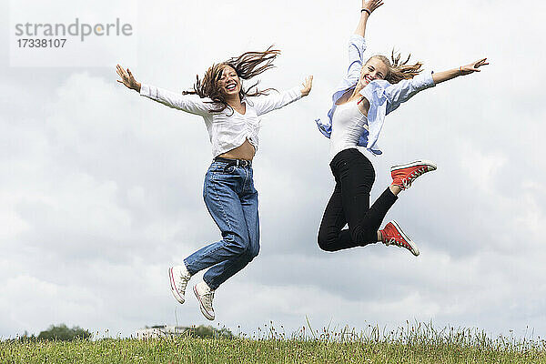 Fröhliche junge Frauen springen auf Gras