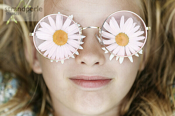 Lächelndes Mädchen mit Kamillenblütenbrille