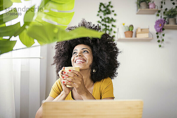 Glückliche Geschäftsfrau mit Kaffeetasse träumt im grünen Haus